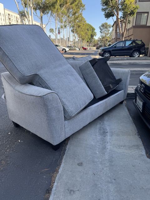Two-piece gray sofa on a San Diego street staged for couch removal