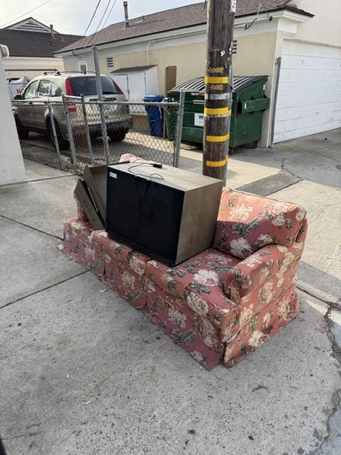 Floral couch staged in a San Diego alley for couch removal