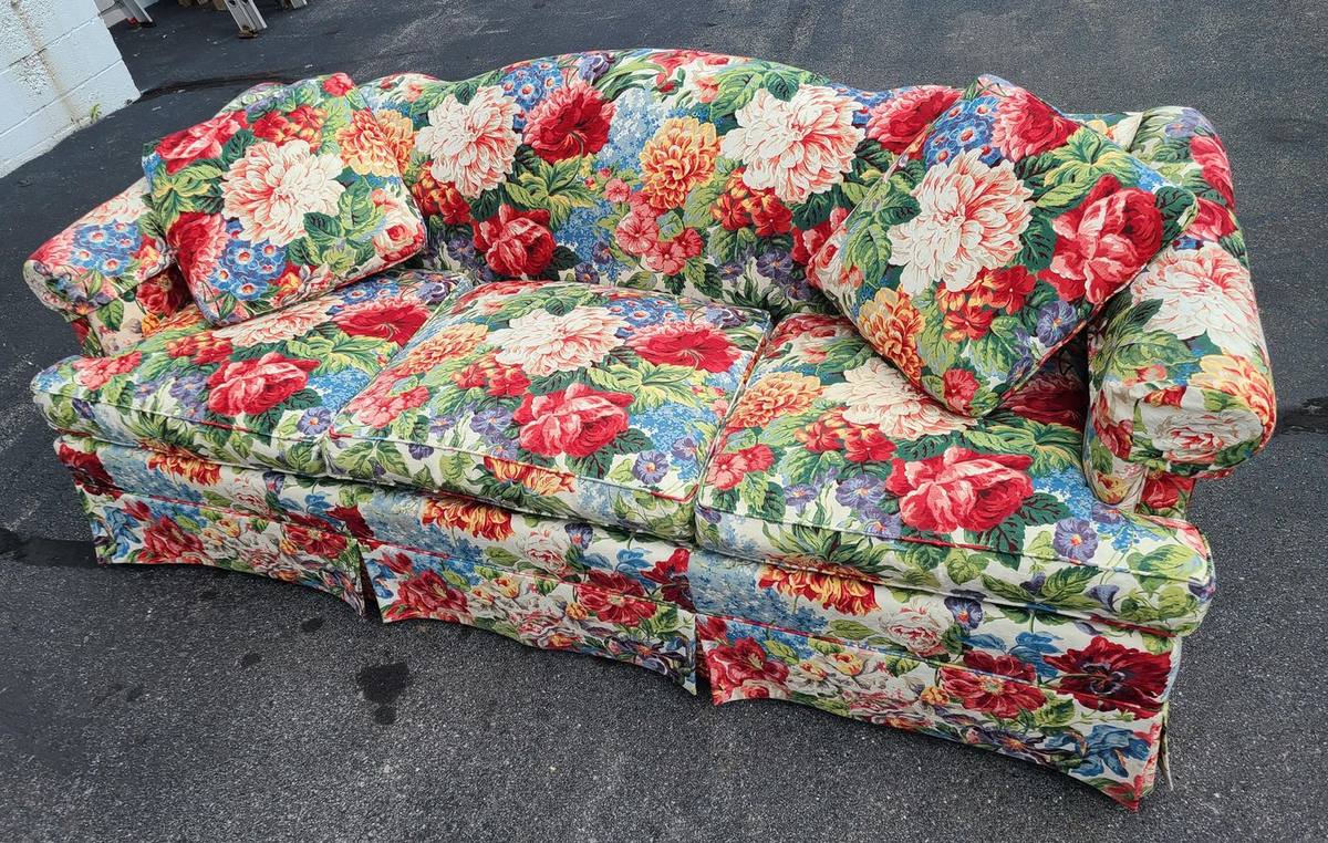 Floral three-seat sofa on pavement ready for sofa pickup