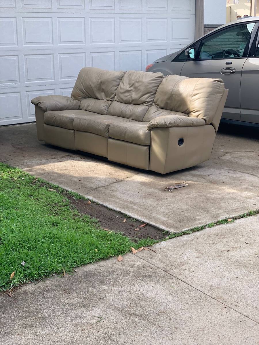 Tan leather recliner sofa on a driveway for curbside sofa removal