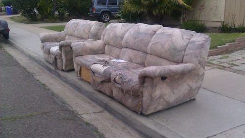Two worn sofas on a San Diego sidewalk for sofa disposal
