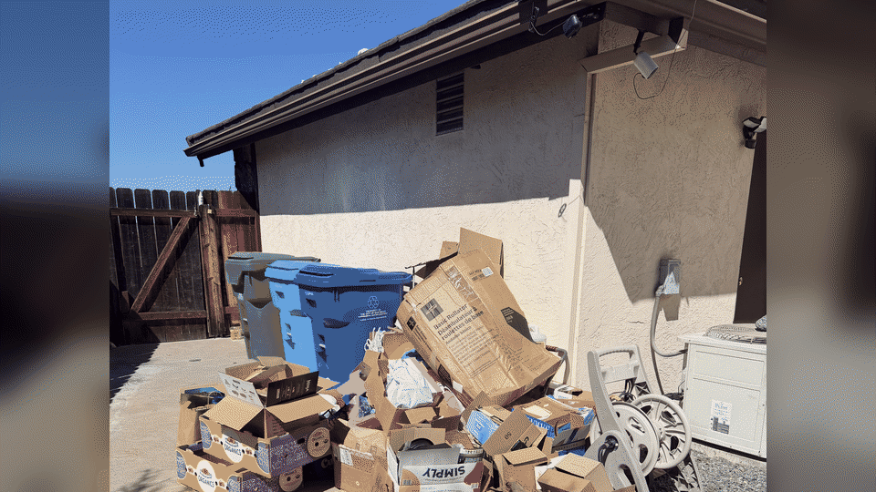Full-service trash hauling in Del Cerro, San Diego. Fred's crew carries cardboard boxes and household trash from a back yard to the junk truck.