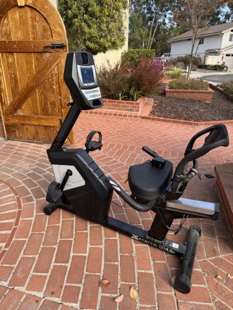 Recumbent exercise bike on a brick patio ready for haul away