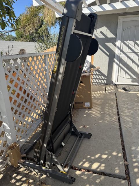 Folded treadmill staged on a San Diego patio for fitness equipment removal