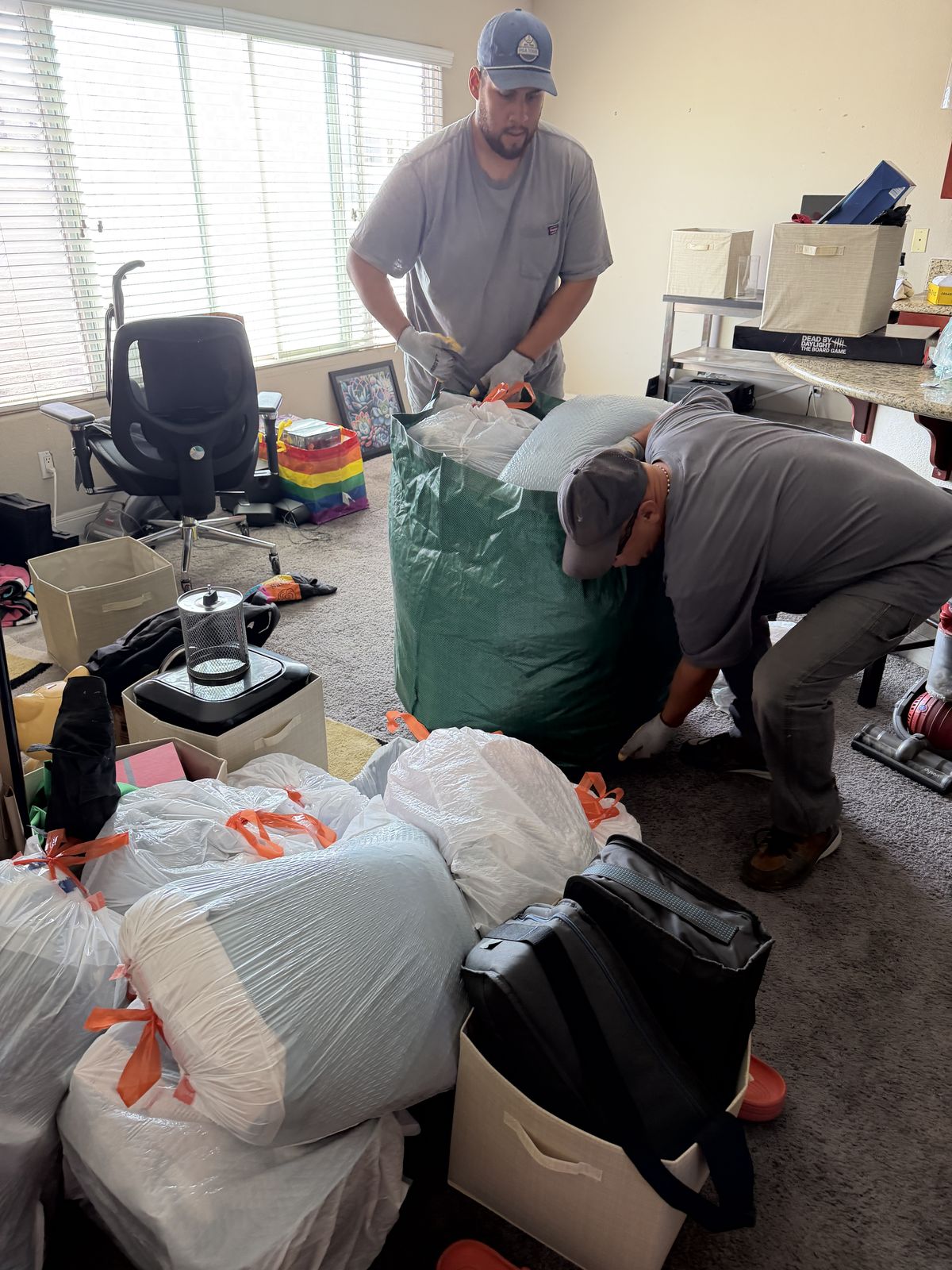 Fred's crew packing bagged household trash into a green hauling bag during a full-service San Diego cleanout