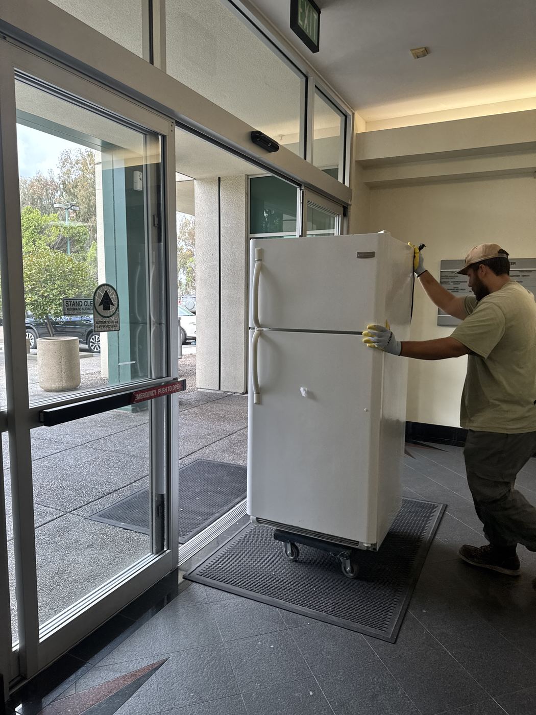 Fred's crew rolling a refrigerator out of a San Diego building lobby for appliance junk removal
