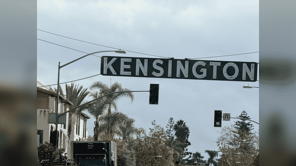 Full-service furniture removal in Kensington, San Diego. Two men carry a mattress and a two-piece sectional down outdoor apartment stairs.