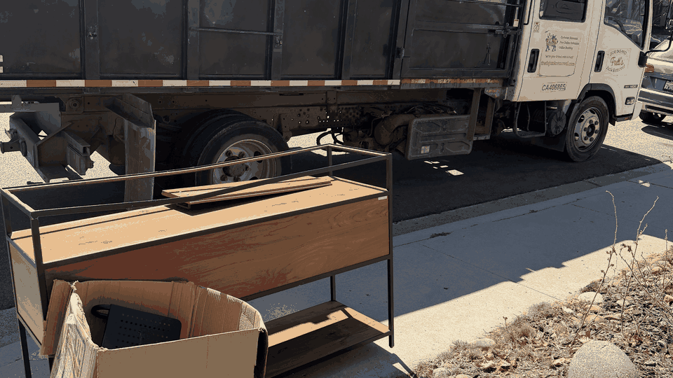 Same-day curbside junk removal in Pacific Beach, San Diego. Fred's crew loads a console table and a cardboard box into the dump truck.