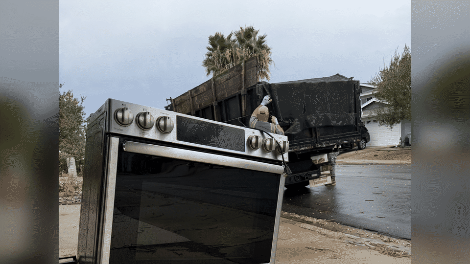 Curbside appliance removal in Serra Mesa, San Diego. Fred's crew loads a stainless range from the curb into the junk truck.