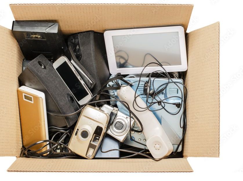 Open cardboard box of phones, cameras, and small electronics for e-waste recycling