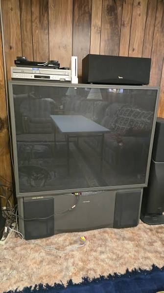 Large projection TV against a wood wall ready for TV recycling