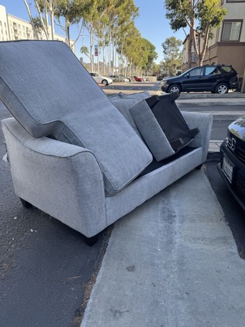 Two-piece gray sofa on a San Diego street staged for couch and sofa removal